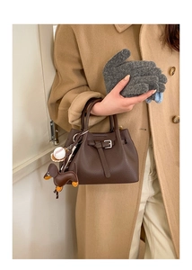 Detail der dunkelbraunen Lederhandtasche mit Gürtelschnalle und Taschenanhängern