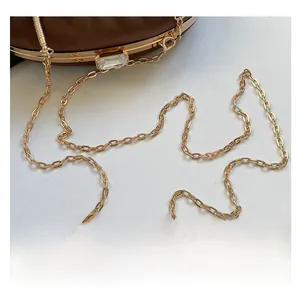 Détail de la bandoulière chaîne dorée et du fermoir en cristal sur le sac à main marron
