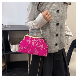 Detail of fuchsia satin evening bag with floral embroidery and large pearl handle strap