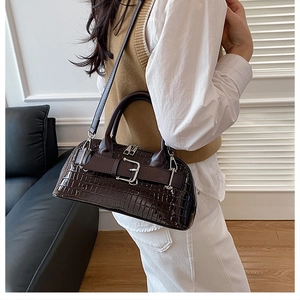 Deep brown crocodile texture shell bag with adjustable strap worn by model in a room
