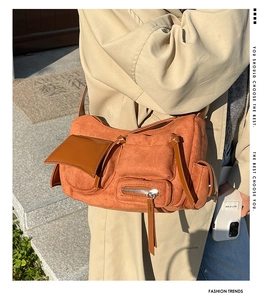 Close-up of ginger yellow crossbody bag showing suede texture and multi-pocket design