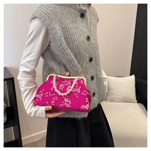 Detail of pink satin evening bag with floral embroidery and elegant pearl chain handle