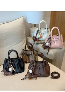 Schicke Lederhandtaschen in mehreren Farben mit dekorativem Gürtel und süßen Anhängern