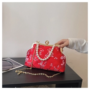 Detail of red satin crossbody bag with floral embroidery and elegant pearl handle