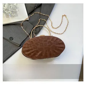 Détail du sac bandoulière plissé marron avec poignées en métal doré et chaîne