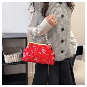 Detail of red floral brocade crossbody bag with pearl handle and golden chain strap