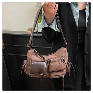 Detail of vintage brown suede and patent leather crossbody bag with multiple utility pockets