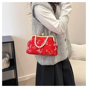 Model showing a vintage red embroidered handbag with a pearl handle and gold chain strap