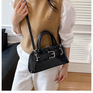 Close-up of black crocodile pattern patent leather shell bag with silver buckle