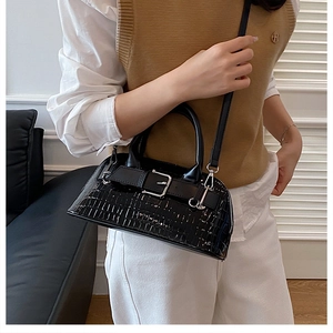 Detail shot of a black crocodile pattern shell bag worn cross-body on a model