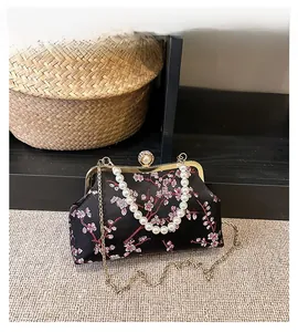 Detail view of black satin evening bag with plum blossom embroidery and pearl chain