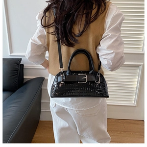 Detailed view of crocodile pattern shell bag with top handle and slim shoulder strap