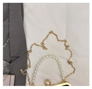 Detailed macro of pearl handle and gold chain on the floral print evening shell bag