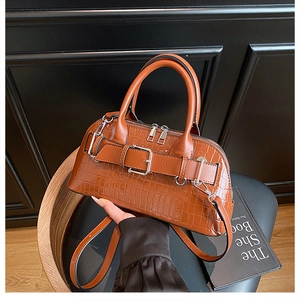 Close-up of caramel crocodile texture handbag with decorative strap and silver hardware