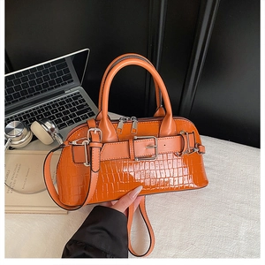 Detail of bright orange crocodile embossed shell bag with silver hardware and strap