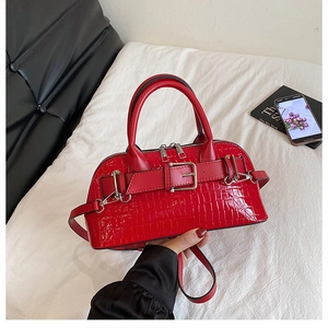 Detail of bright red crocodile texture handbag with silver hardware and dual handles