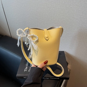 Yellow litchi leather bucket bag featuring pearl charm and white lace bow decoration