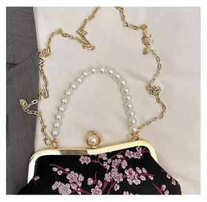 Detail of vintage black bag with pink floral embroidery and pearl handle with gold chain