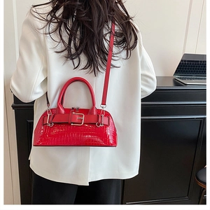 Detail of red crocodile textured shell bag with belt buckle on white blazer