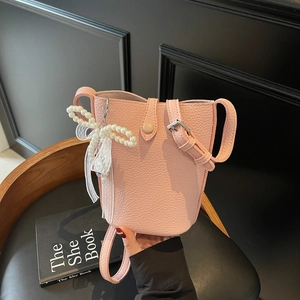 Pink lychee leather bucket bag with pearl bow and lace ribbon detail, handheld pose