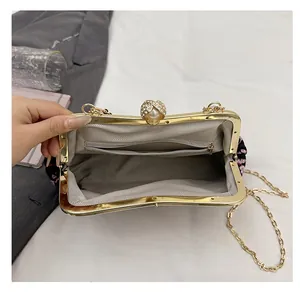 Detail of evening bag interior with floral fabric, pearl clasp and chain strap