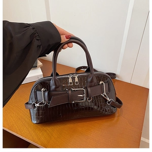 Detail of dark brown crocodile pattern shell bag with silver buckles and dual handles