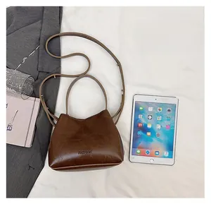 Detail view of small vintage brown leather bucket bag with top handle and fashion debossing