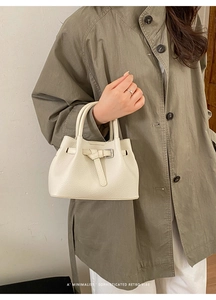 Detailansicht der cremeweißen Lederhandtasche mit Gürtelschnalle und Doppelgriffen