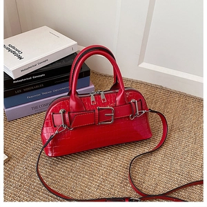 Detail of red crocodile pattern shell bag with buckle strap on a woven mat