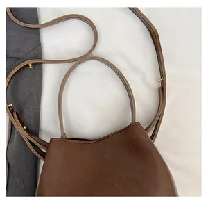 Detail of dark brown faux leather bucket bag showing adjustable strap and golden buckle