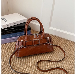 Detail of brown crocodile pattern shell bag with glossy finish and metal buckle decoration