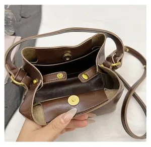 Detail view of the deep brown leather bucket bag showing the golden magnetic closure buckle