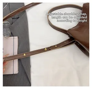 Detail of adjustable brown leather strap with gold buckle on vintage bucket bag
