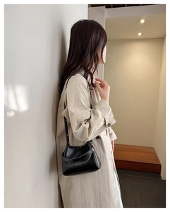 Detail shot of black minimalist crossbody bucket bag with adjustable shoulder strap