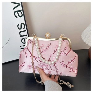 Detailed view of pink satin evening bag with cherry blossom embroidery and pearl handle