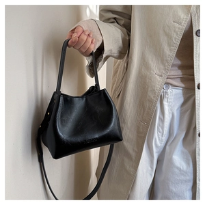 Detail of black matte leather bucket bag with embossed Fashion lettering and crossbody strap