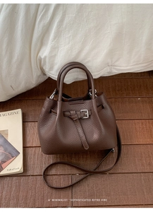Nahaufnahme einer dunkelbraunen Eimer-Tasche aus Leder mit dekorativem Gürtelverschluss