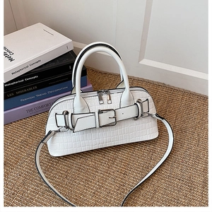 Detail of white crocodile embossed shell bag with silver buckle and leather strap
