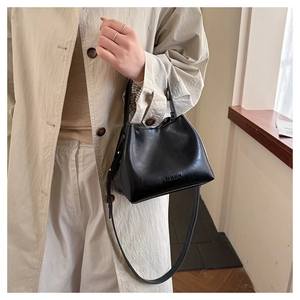 Detail of a black pebbled leather bucket bag featuring fashion embossing and a top handle