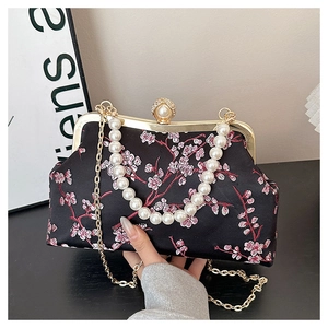 Close-up of black floral embroidery and elegant large pearl handle on evening clutch bag
