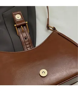Detail of vintage brown leather texture and premium gold magnetic clasp on shoulder bag