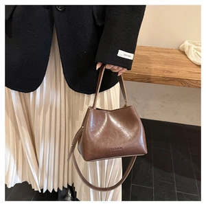 Close-up of a dark brown glossy leather tote bag with FASHION text and long shoulder strap