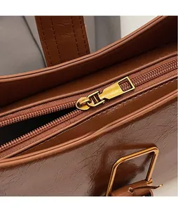 Detail of dark brown vintage textured leather bag with polished gold metal zipper slide