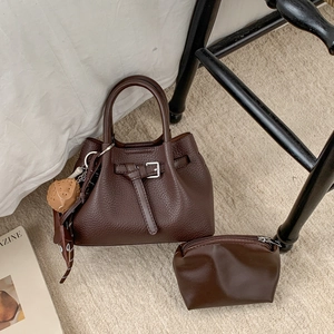 Detail eines dunkelbraunen Lederhandtaschen-Sets mit Gürtelschnallen und kleiner Tasche