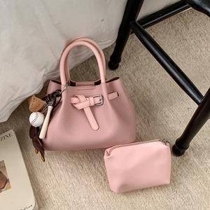Detailansicht der rosa Handtasche aus Leder mit Gürtel-Deko und sportlichem Anhänger