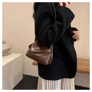 Detail of dark brown leather shoulder bag with FASHION embossing and long strap