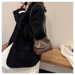 Close-up of a dark brown glossy leather bucket bag featuring an embossed FASHION logo