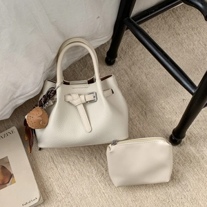 Nahaufnahme cremefarbene Leder-Handtasche im Set mit Schnallendetails und Tieranhänger