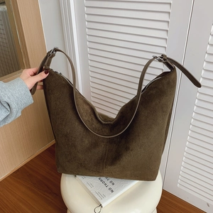 Brown suede leather Hobo bag with wide strap and silver buckle on a white stool