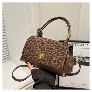 Detail of leopard print handbag with plush texture and gold clasp on brown leather
